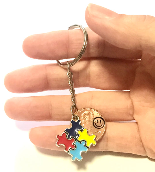 Autism Awareness Puzzle Piece Charm Lucky Penny Keychain with Smiley Face engraving above the date on a Lincoln Cent.