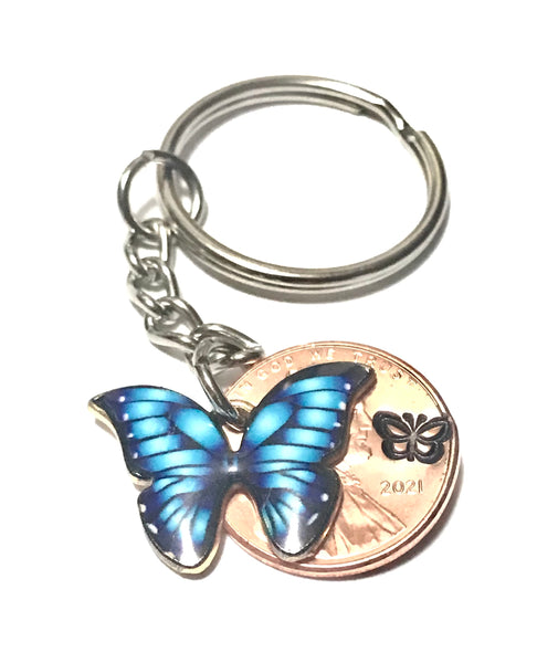 Blue Monarch Butterfly sized beside a Lincoln Cent  showing the hand stamp butterfly engraving above the date.