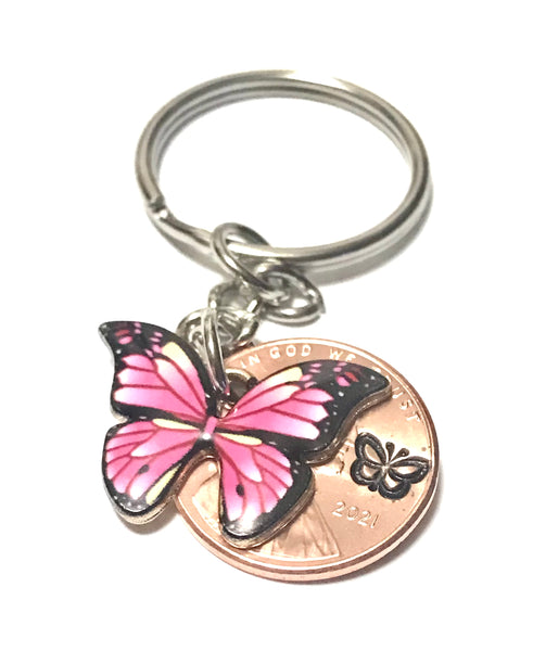 Pink Monarch Butterfly sized beside a Lincoln Cent showing the hand stamp butterfly engraving above the date.