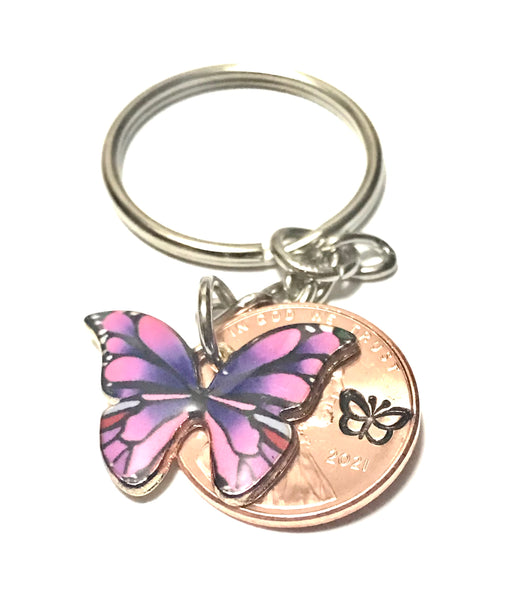 Purple Monarch Butterfly sized beside a Lincoln Cent showing the hand stamp butterfly engraving above the date.