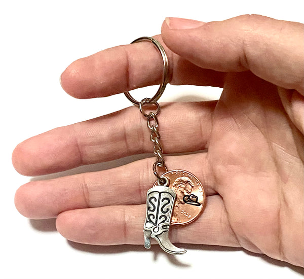 A Silver Cowgirl Boot charm attached to a Lincoln Cent with a cowgirl hat engraved above the date on this 3" Lucky Penny Keychain.
