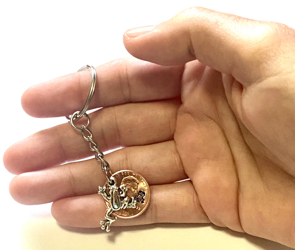 Frog Lucky Penny Keychain with a silver frog charm attached to a Lincoln Cent showing an engraving of a happy frog.