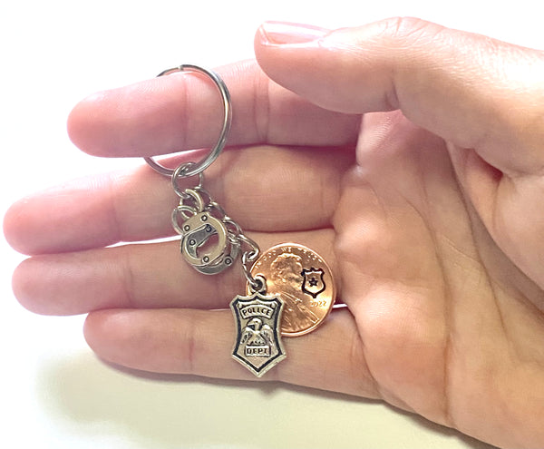 Police Department Lucky Penny Keychain with a silver shield charm and silver set of handcuffs along with an engraved shield with a star on a Lincoln Cent.