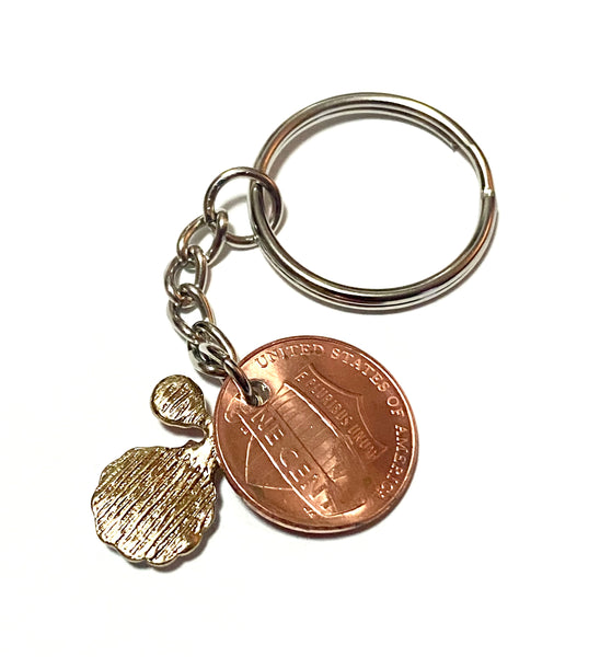 A Lucky Penny Keychain with a rhinestone charm of a vintage perfume bottle and atomizer attached to a Lincoln Cent with a perfume bottle silhouette above the date.