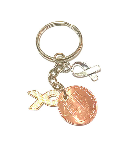 A purple awareness ribbon charm along with a silver HOPE charm attached to a Lincoln Cent with a detailed design of an awareness ribbon above the date for a great Lucky Penny Keychain.