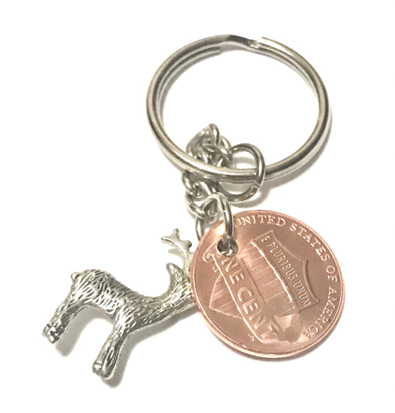 A Silver Deer Charm with an Antler Stamp engraved above the date of a Lincoln Cent to make a Lucky Penny Keychain.