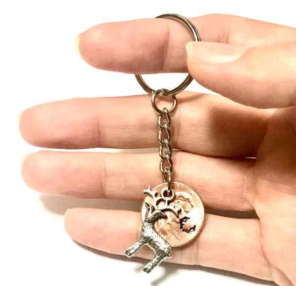 A Silver Deer Charm with an Antler Stamp engraved above the date of a Lincoln Cent to make a Lucky Penny Keychain.