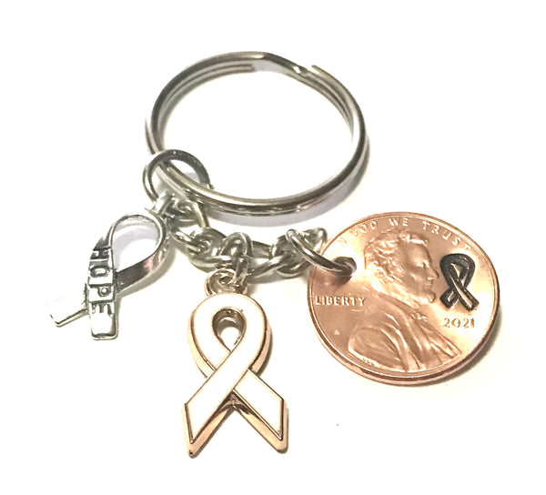 This Lung Cancer Awareness White Ribbon Charm Lucky Penny Keychain includes a Silver Ribbon engraved with the word "HOPE," and is paired with a Lincoln Cent that has a matching ribbon design above the date.