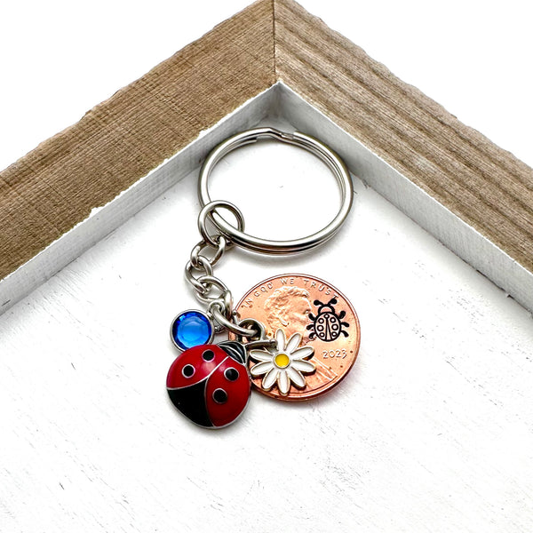 Red ladybug charm, flower charm, and birthstone with a hand stamped penny.