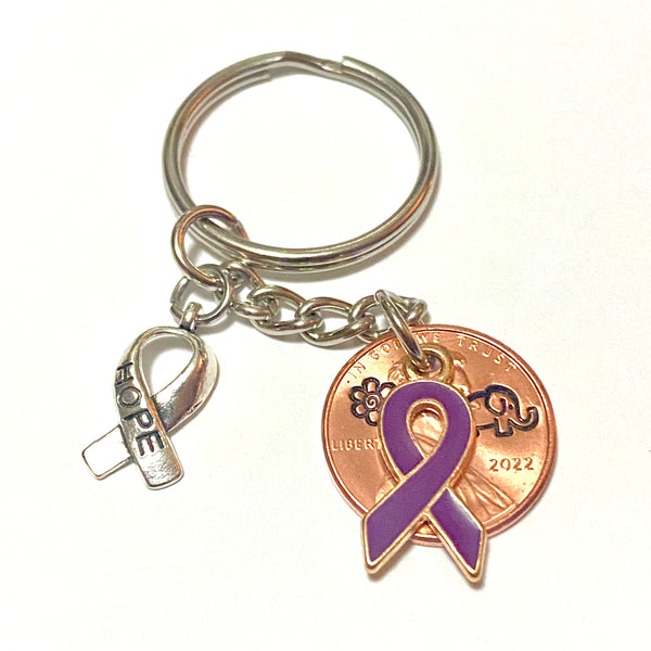 Alzheimer's Awareness Purple Ribbon Charm attached to a silver Hope Ribbon on a 3 inch Lucky Penny Keychain. A hand stamped elephant and forget-me-not flower are engraved above the date on the penny.