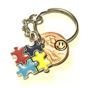 Autism Awareness Puzzle Piece Charm Lucky Penny Keychain with Smiley Face engraving above the date on a Lincoln Cent.