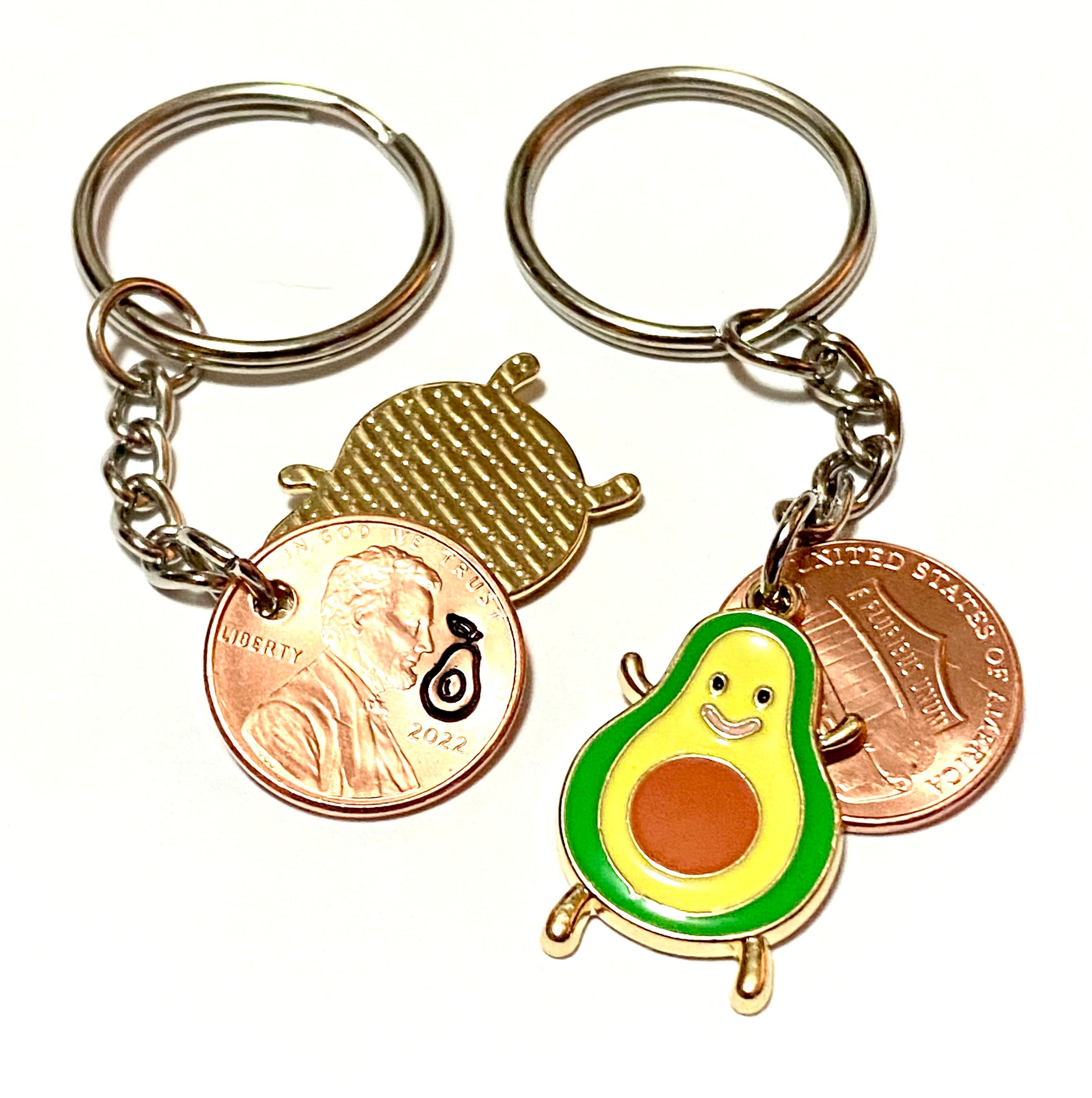 An avocado fruit lucky penny keychain with an engraved avocado above the date of a Lincoln Cent attached to an avocado charm.