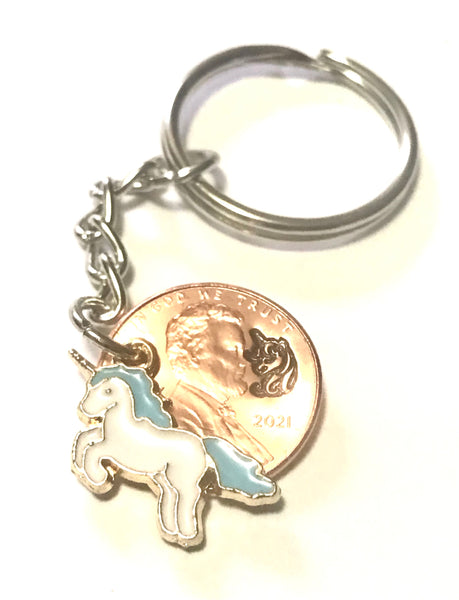 A Unicorn Lucky Penny Keychain with a Unicorn Charm with a Blue Mane and Tail with a hand stamped design above the date of a Lincoln Cent.