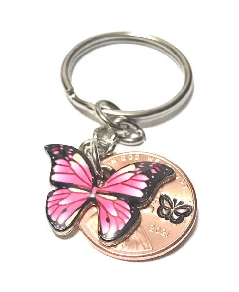 Pink Monarch Butterfly sized beside a Lincoln Cent showing the hand stamp butterfly engraving above the date.