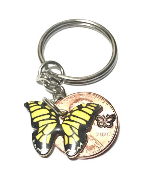 Yellow Monarch Butterfly sized beside a Lincoln Cent showing the hand stamp butterfly engraving above the date.