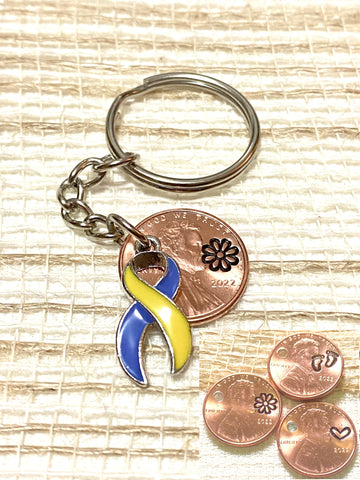 A yellow and blue Down Syndrome Awareness Ribbon Charm attached to a Lincoln Cent with an engraving of your choice above the date. Choose footprints, a daisy, or heart shaped stamp.
