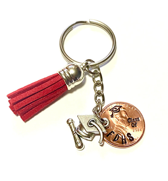 A Lucky Penny Keychain from Palmetto Charms & Etc. with a red tassel and a graduation cap and diploma silver charm.