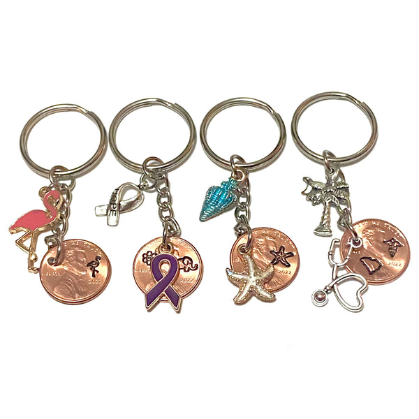 A Collection of Lucky Penny Keychains from Palmetto Charms and Etcetera including the Flamingo, Seashell, SC Nurse, and Alzheimer's Awareness designs.