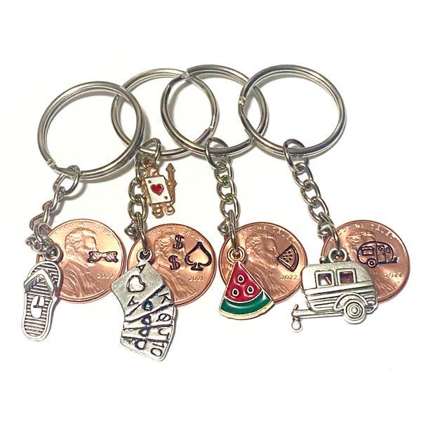 A collection of several Lucky Penny Keychains by Palmetto Charms & Etc. including Summer Fun, Poker, Watermelon, and Camper Charms with detailed hand stamped designs above the date on the penny.