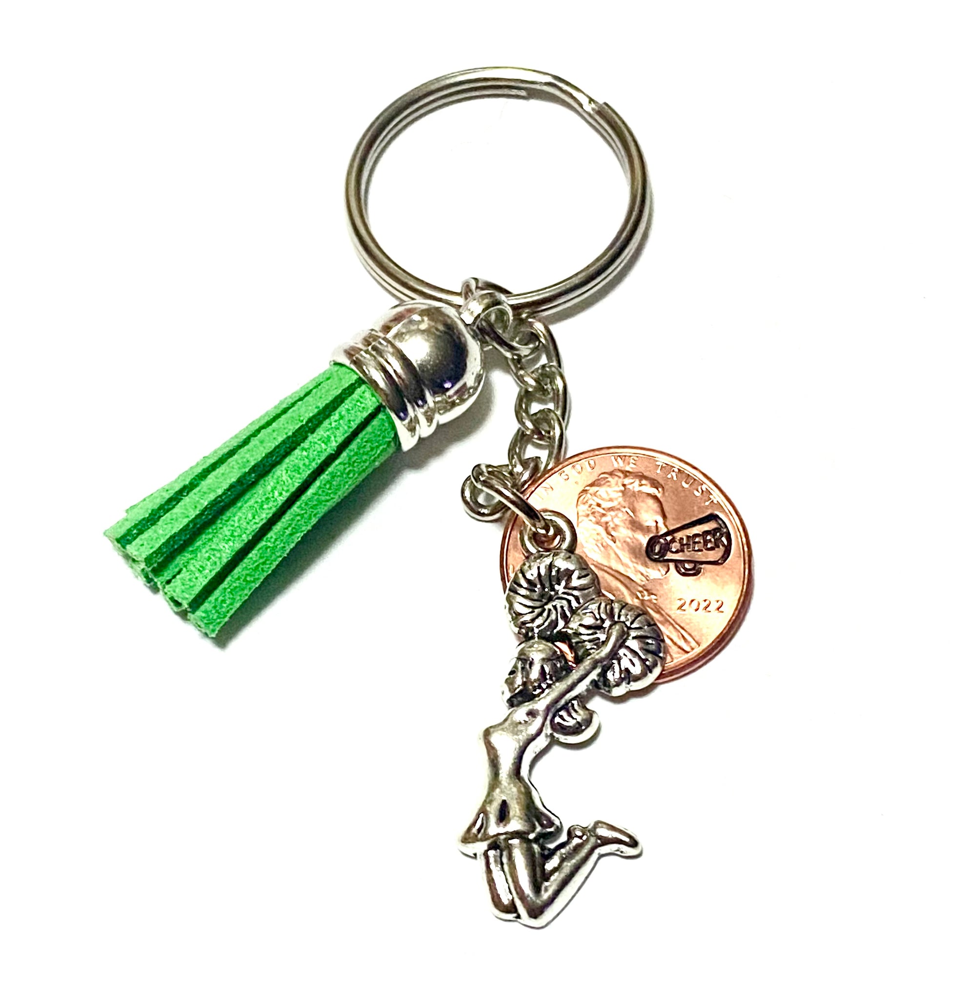 A silver charm featuring a cheerleader with pom poms attached to a lucky penny with a detailed cheer megaphone design. Also attached is a green tassel.