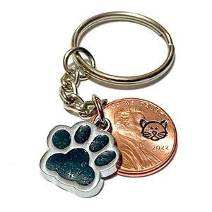 A black glitter charm of a cat's paw with a hand stamped penny with a cat's face on a lucky penny keychain.