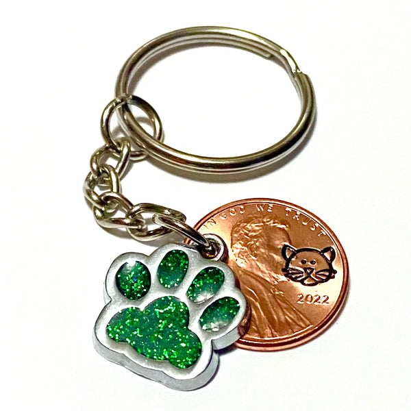 A green glitter charm of a cat's paw with a hand stamped penny with a cat's face on a lucky penny keychain.