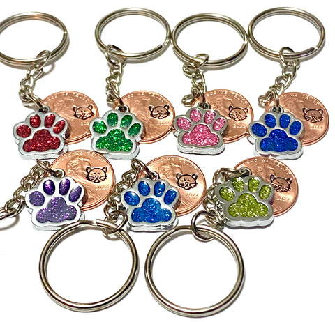 Cat face glitter paw print lucky penny keychains with cat's face engraved on penny and matched with a glitter charm paw print. Choose from black, blue, light blue, red, pink, purple, yellow, or green.