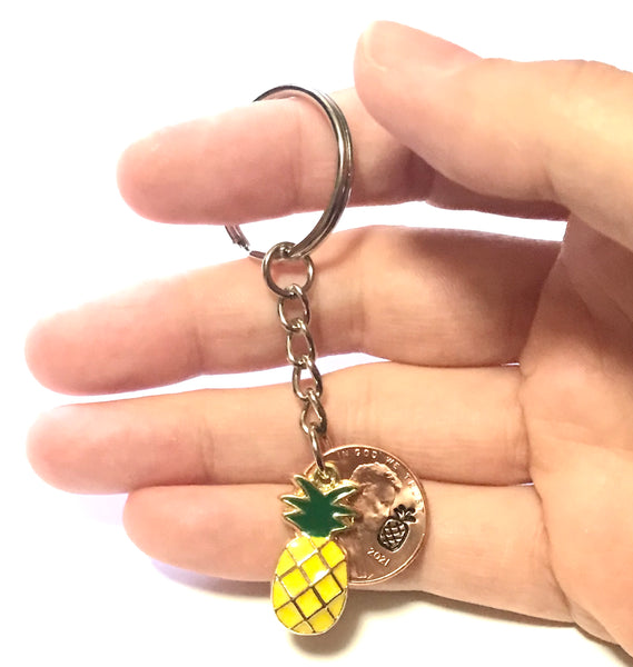 Pineapple Golden Fruit Charm Lucky Penny Keychain alongside a hand stamped Lincoln Cent with a Pineapple engraving above the date.