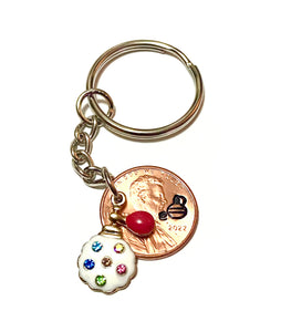 A Lucky Penny Keychain with a rhinestone charm of a vintage perfume bottle and atomizer attached to a Lincoln Cent with a perfume bottle silhouette above the date.