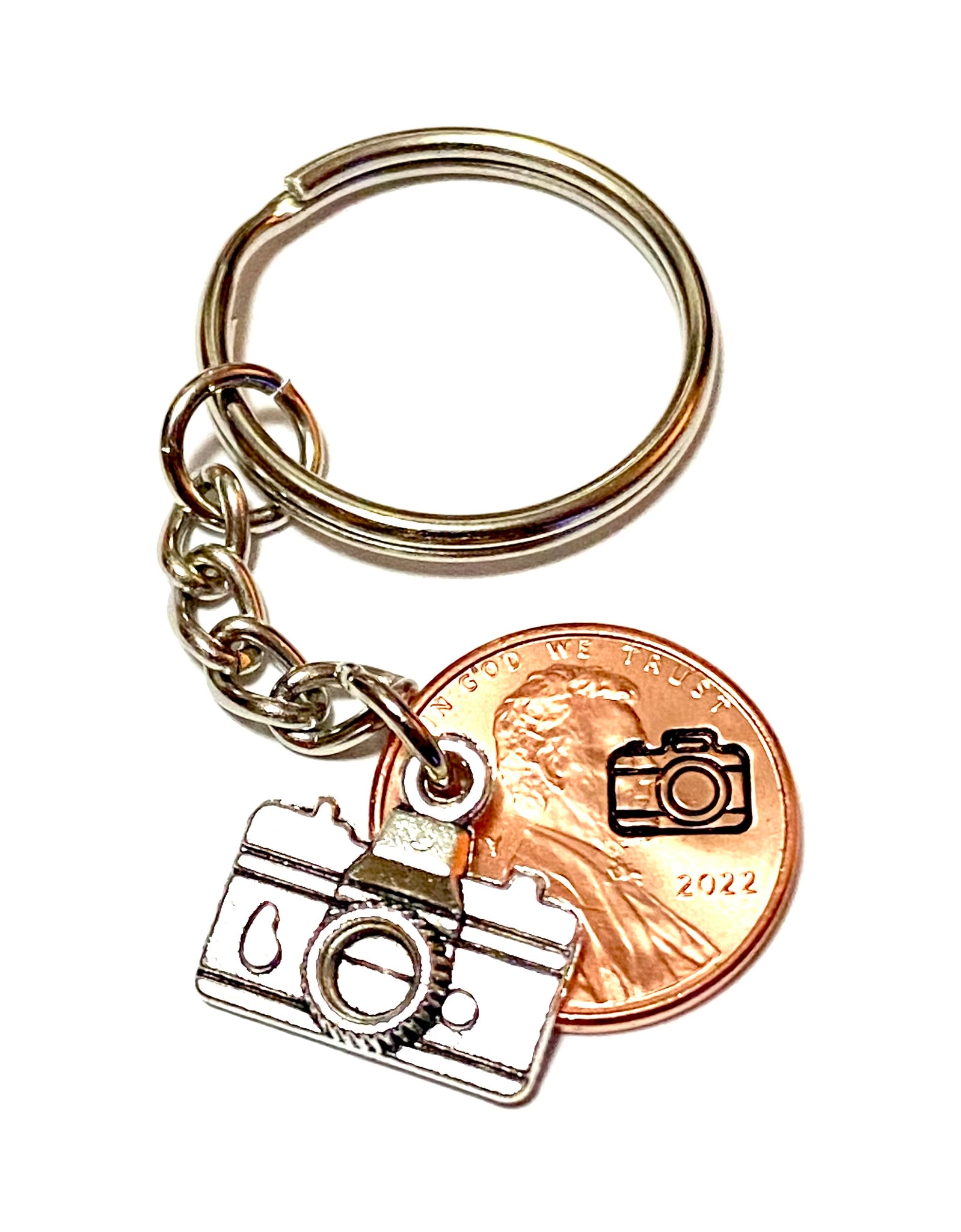 A photography inspired keychain with a silver camera charm attached to a Lincoln Cent with a camera design engraved above the date. It's an awesome Lucky Penny Keychain!