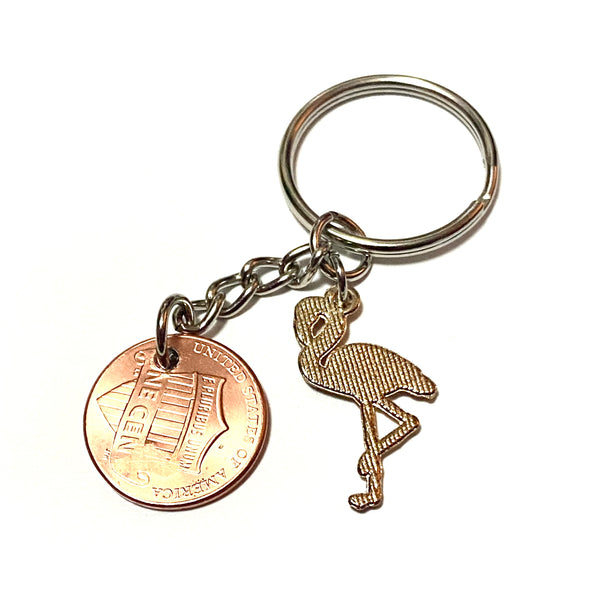 A Pink Flamingo keychain with a stamped flamingo bird above the date of a Lincoln Cent with a Pink Flamingo charm on this Lucky Penny Keychain.