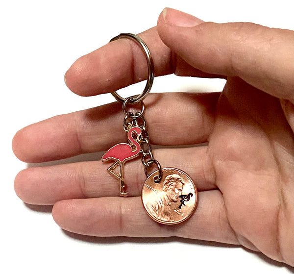 A Pink Flamingo keychain with a stamped flamingo bird above the date of a Lincoln Cent with a Pink Flamingo charm on this Lucky Penny Keychain.