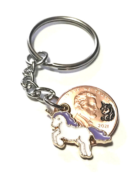 A Unicorn Lucky Penny Keychain with a Unicorn Charm with a Purple Mane and Tail with a hand stamped design above the date of a Lincoln Cent.