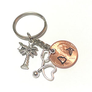 A Lucky Penny Keychain with a Palmetto Tree and Crescent Moon charm, along with a silver Stethoscope Heart Charm.